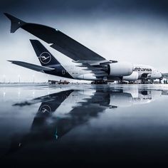 an airplane is parked on the tarmac with its wing extended and it's reflection in the water