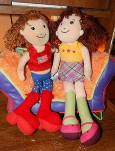 two stuffed dolls sitting on top of a chair