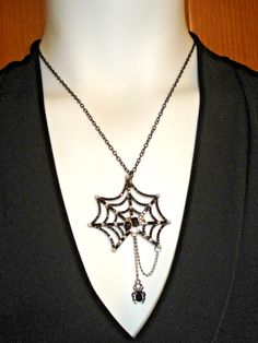 a white mannequin wearing a black necklace with spider web and beads on it