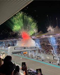 fireworks are lit up in the air above a race track as spectators watch from the stands