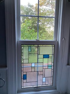 a window with blue squares on it in front of a white wall and windowsill