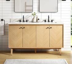 a bathroom with two sinks and mirrors on the wall next to a rug in front of it