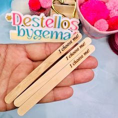 a person holding two wooden clothes pins with the words destellos bygena on them