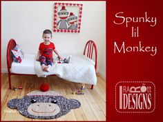 a little boy sitting on top of a bed next to a monkey pillow and rug