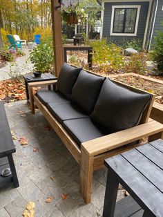 a wooden bench sitting on top of a patio next to a black table and chairs