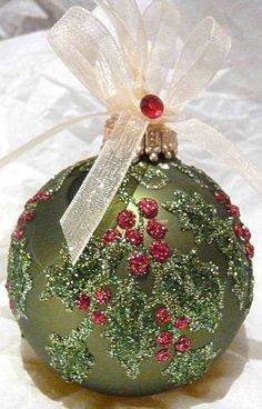 a green christmas ornament with red berries on it