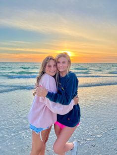 two girls hugging each other on the beach