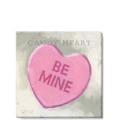 a candy heart with the words be mine painted on it in pink and grey colors