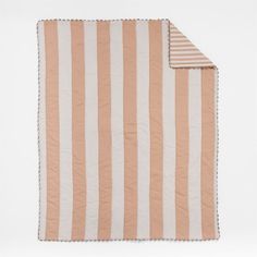 an orange and white striped blanket folded on top of a tablecloth with a black border