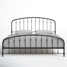 an iron bed frame with white sheets and pillows