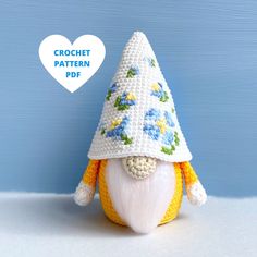 a crocheted gnome with a white hat and blue flowers on it's face