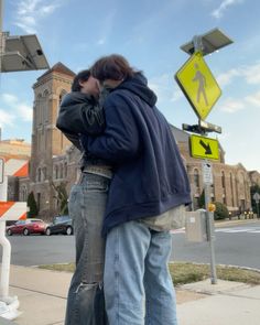 two people standing next to each other in front of a cross walk sign and street signs