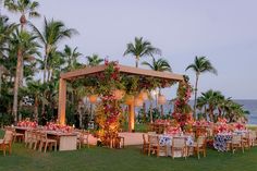 an outdoor dining area with tables and chairs set up for dinner on the lawn next to the ocean