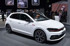 a white volkswagen car is on display at an auto show