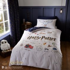 a harry potter themed bed spread with an owl and hogwarts symbols on it