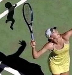 a woman holding a tennis racquet on top of a tennis court with a shadow behind her