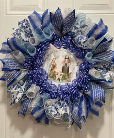 a blue and white wreath hanging on the front door with a photo in it's center