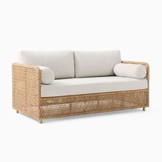 a wicker couch with white cushions and pillows on it's backrests