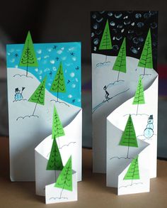 two paper snowmen with trees on them, one is white and the other is green