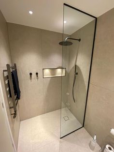 a bathroom with a walk in shower next to a toilet and a towel dispenser