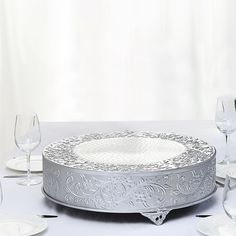 a white table topped with a cake covered in frosting next to empty wine glasses