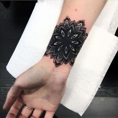 a woman's arm with a black and white flower tattoo on the left wrist