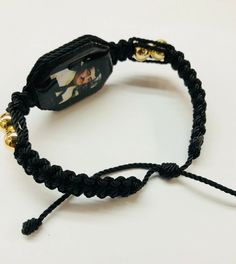 Pulsera hecha a mano de Jesus Malverde doble tejida con hilo reforzado en color negro y bolas chapeado en oro laminado es una pulsera ajustable para hombre o mujer material: hilo reforzado#18 color negro bolas dorado 8mm en oro laminado tableta de madera color negro con imagen de Jesus Malverde por ambos cubierta con resina para no despintarse en cuando suda al usarse Tambien se puede hacer de diferente color de hilo, preguntenos!! porque lo hacermos la pulsera en cuando lo ordena Spiritual Braided Bracelet Jewelry, Adjustable Braided Bracelet Jewelry, Adjustable Braided Jewelry Bracelet, Adjustable Gold Bead Bracelet As Gift, Adjustable Gold Beads Bracelet As Gift, Adjustable Braided Bangle Jewelry, Gold Beaded Friendship Bracelets As Gift, Gold Bohemian Jewelry For Souvenir, Traditional Resizable Jewelry For Friendship