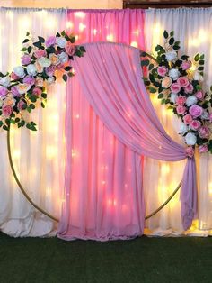 a decorated stage with pink drapes and white flowers on it's back wall