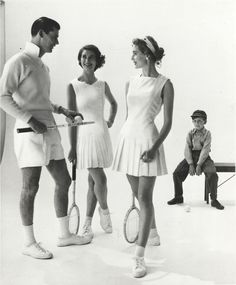 three people are standing with tennis rackets in their hands and one man is sitting on a bench