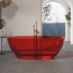 a large red bath tub sitting in the middle of a room next to a window