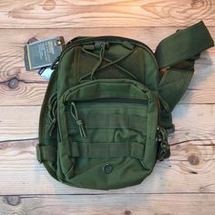 an army green bag sitting on top of a wooden floor