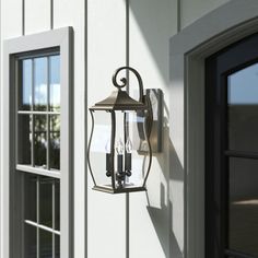 a wall mounted light on the side of a white building with two glass doors and windows