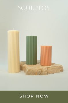 three tall candles sitting on top of a wooden block with the words sculptos