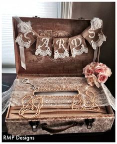 an open suitcase with lace and flowers on the floor next to it is a sign that says