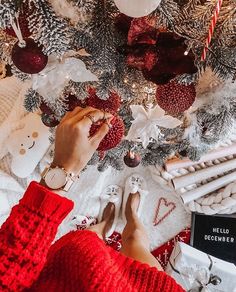 someone decorating a christmas tree with red and white ornaments