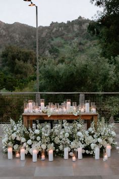 a table with candles and flowers on it in front of some mountains is set up for a wedding