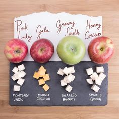 an apple, cheese, and honey cubes on a slate board with a sign