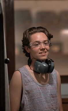 a woman with glasses and a telephone on her neck is standing in front of a door