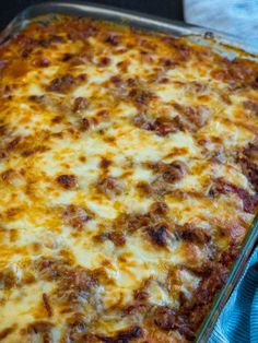 a casserole dish with cheese and meat in it sitting on a blue towel