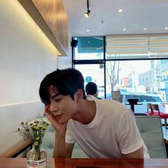 a young man sitting at a table in front of a bottle of wine and cell phone