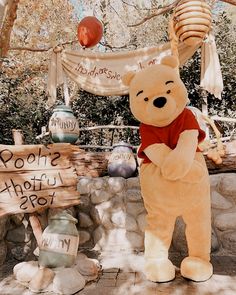 a large teddy bear standing next to a sign