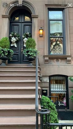 an apartment building with stairs leading up to the front door and two potted plants on either side