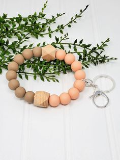 a wooden beaded necklace with two keychains on it and some green leaves