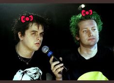 two men with green hair and red bows on their heads, one holding a microphone