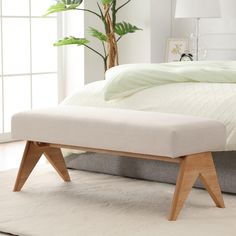 a bed with a white blanket and wooden legs