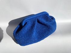 a blue knitted pouch sitting on top of a white table next to a black object