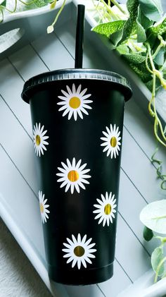 a black cup with white and yellow flowers on it sitting on top of a tray