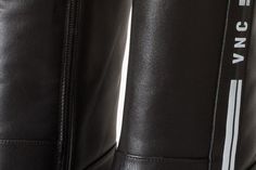 the back side of a pair of black leather boots with white and silver lettering on them