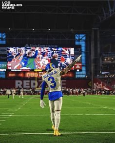 a football player is walking on the field with his arms in the air and one hand up