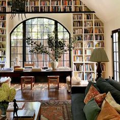 a living room filled with lots of furniture and bookshelves next to a window